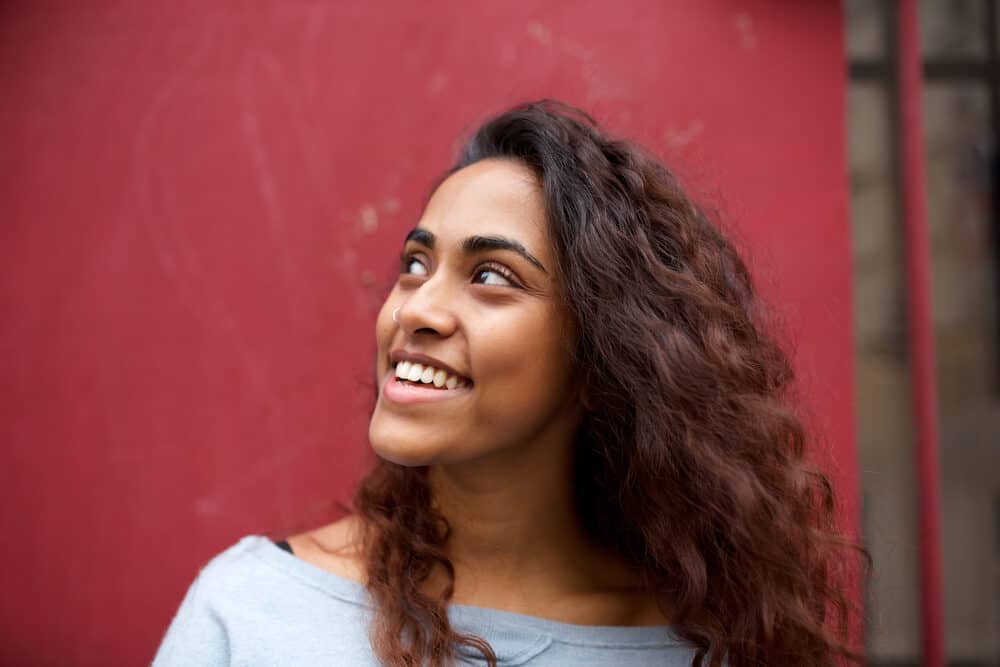 Smiling Indian American girl with warm tones on natural hair styled after using color-protecting shampoo