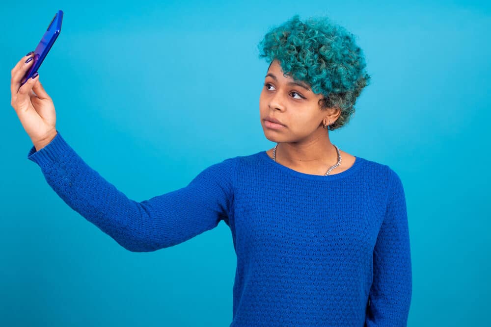 Adult female wearing blue mascara and blue sweater with a silver chain