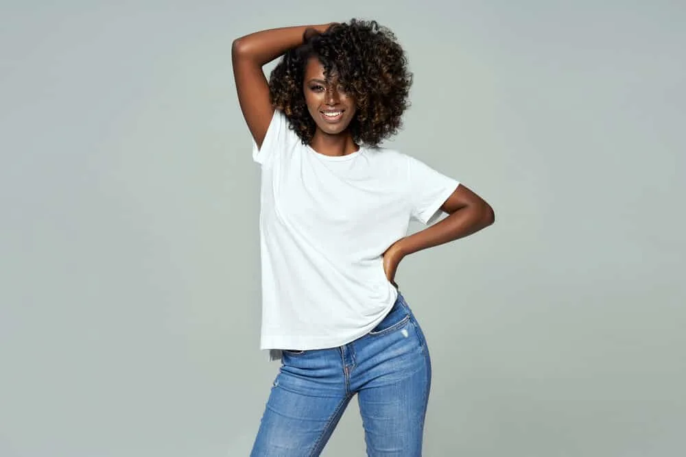 Dark skinned female with low porosity spiral curls wearing stonewashed blue jeans 
