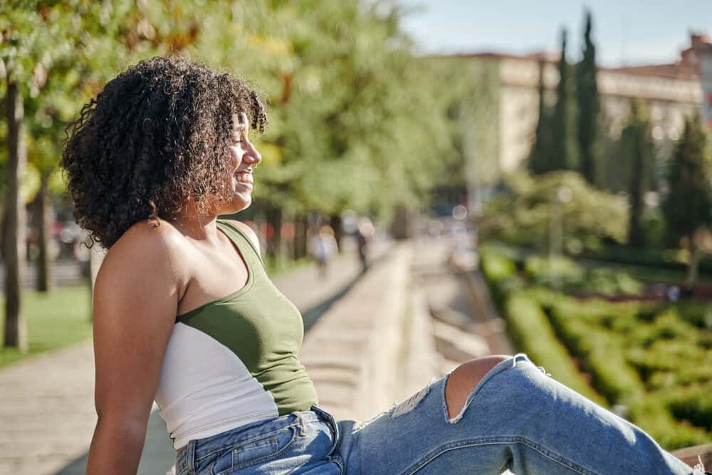 Cute young community college student with curly dry hair sitting outside