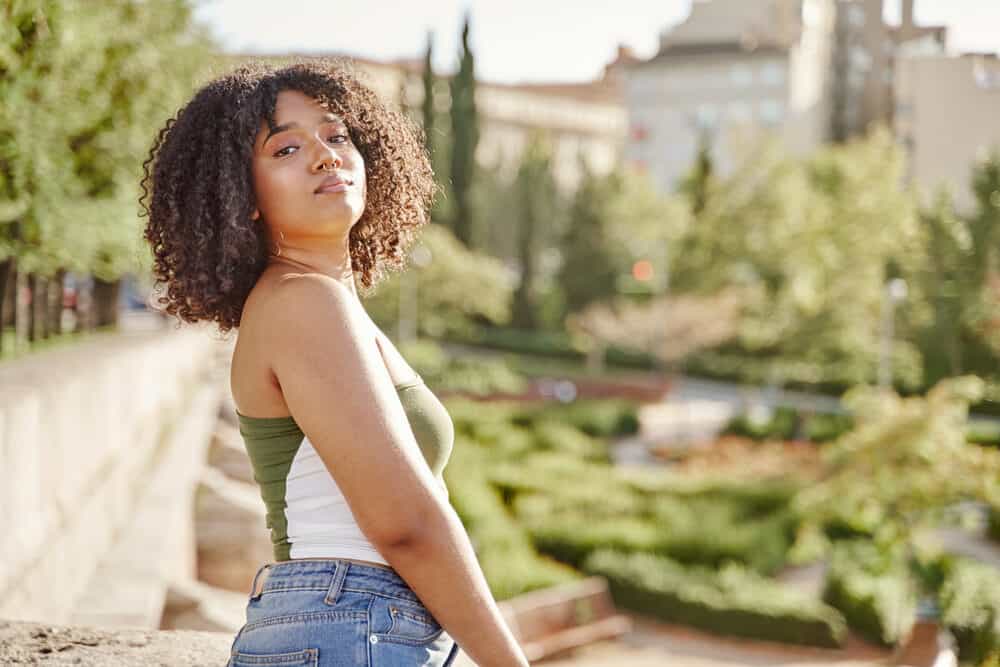 Confident young woman with her head held high standing outside with a bird bath in the background