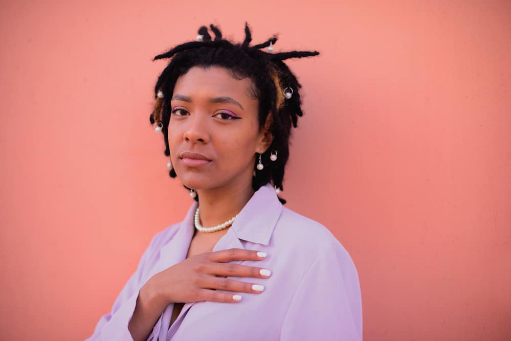 Black woman with dreadlocks with product buildup wearing a purple business suit