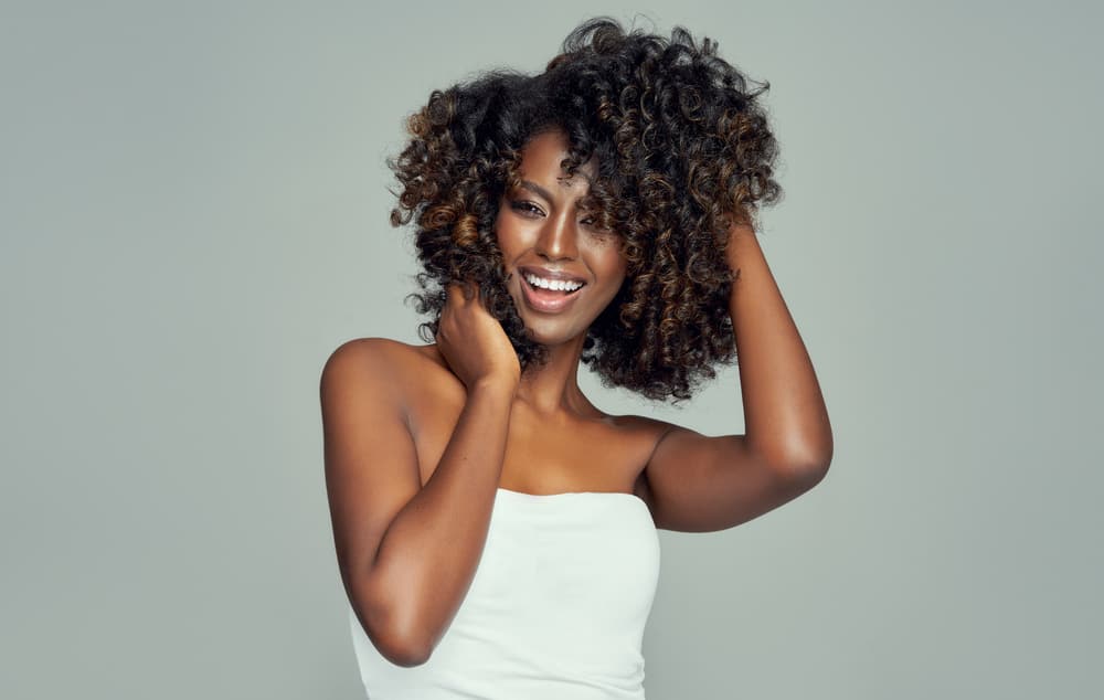 Cheerful black girl brown and black curls following the Curly Girl Method