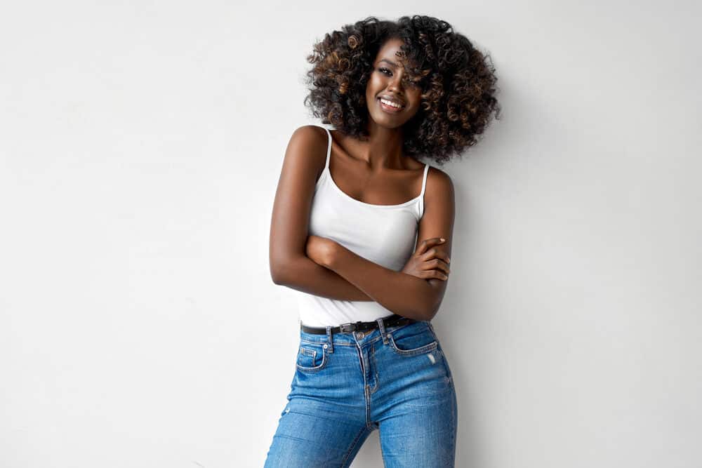 Black girl with curly flat twist styled with Shea Moisture leave-in conditioner wearing a white tank top and blue jeans 