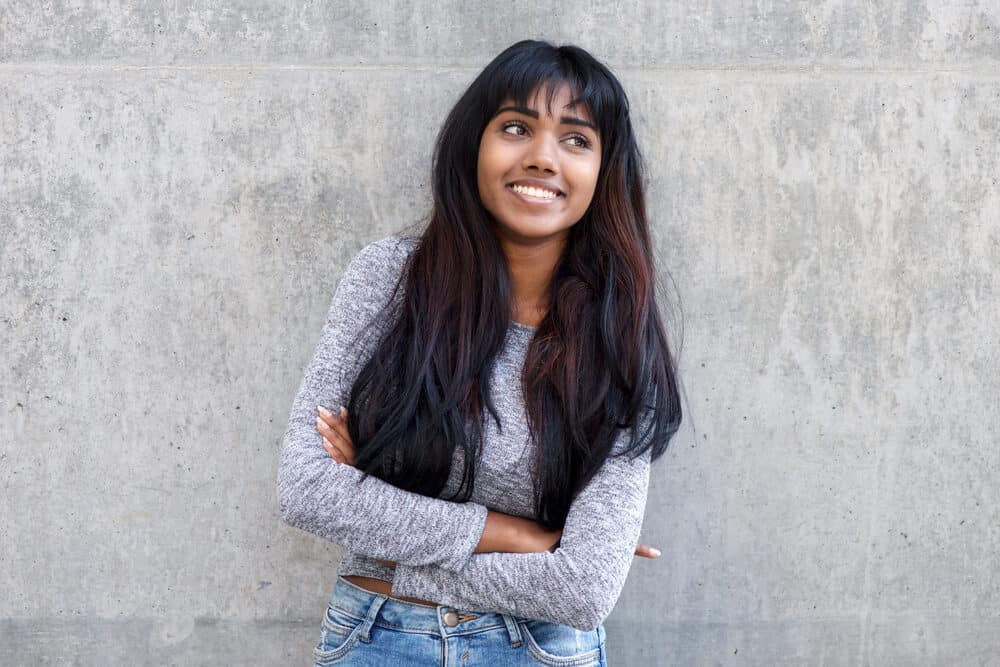 Indian girl with her arms crossed wondering if she could wear a wig if her hair fell out completely