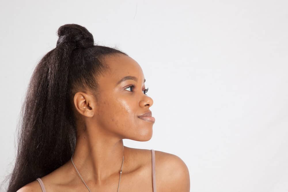 African woman with her face and hair moisturized look into the distance