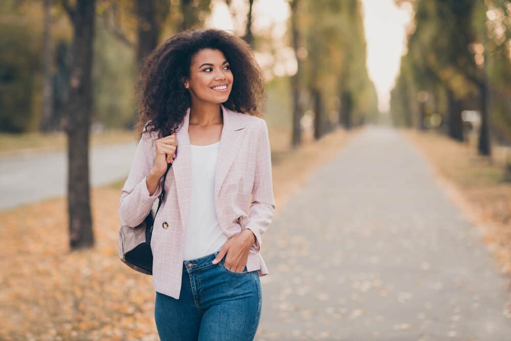 Lady with natural hair without any chemical treatments whatsoever walking through the park in autumn.