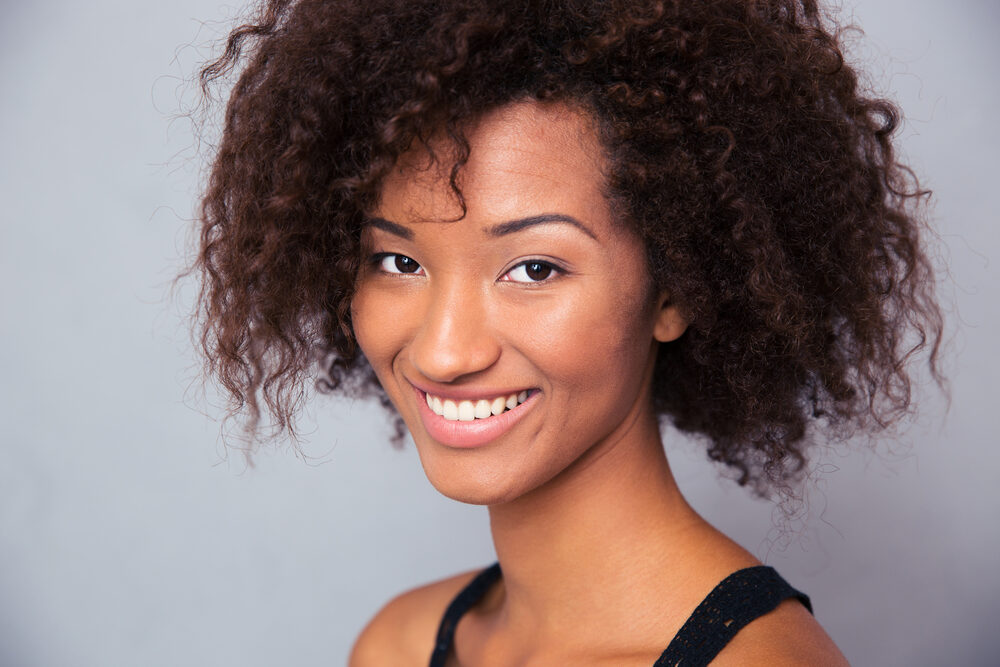 Black girl with a cute smile wearing frizz-free curls styled in a wash and go hairdo.