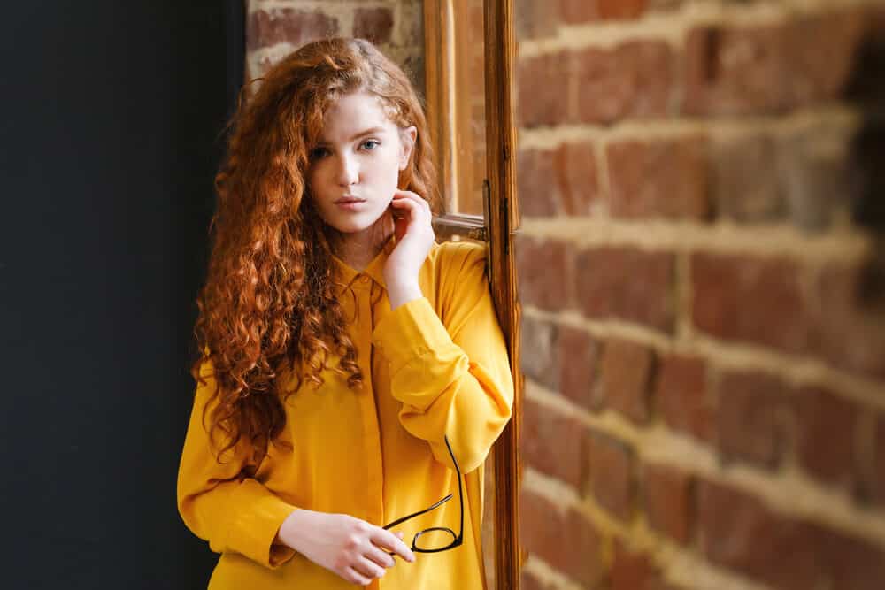 Wavy redhead lady in the yellow-ish dress shirt with naturally straight hair that's been permed. 