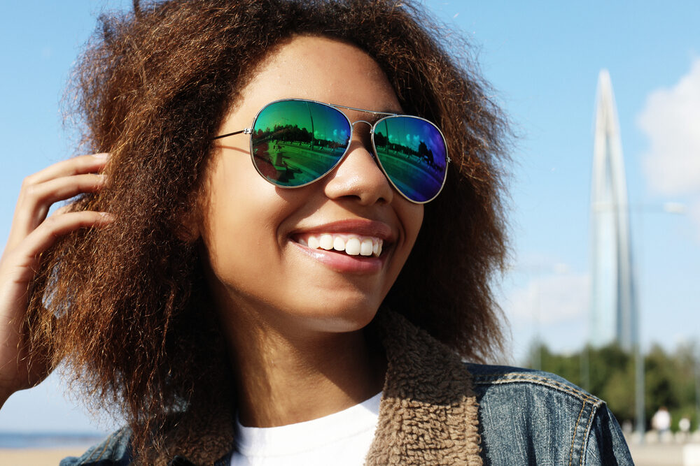 Young African American girl with wild side hair strands looking to smooth existing flyaways with a light hairspray.