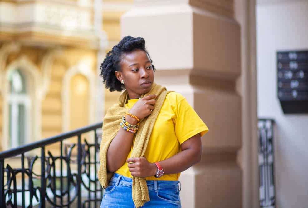 Black woman with completely dry natural hair wearing a yellow shirt and colorful bracelets.