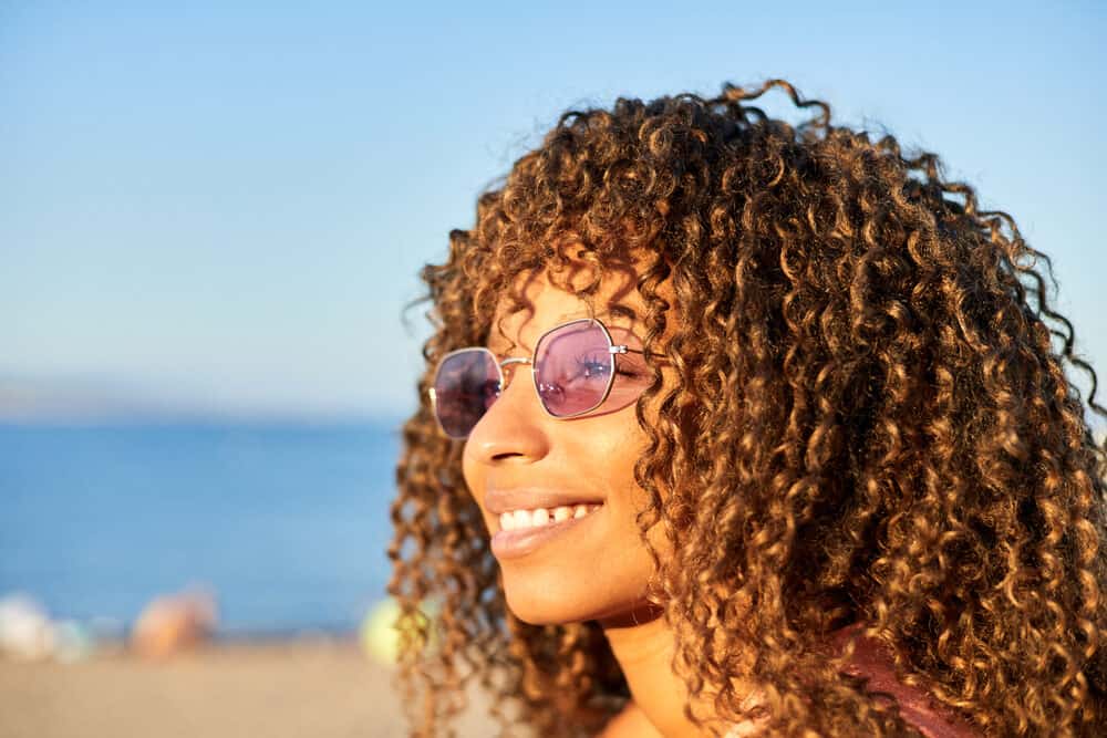 Cute African American female with dark hair with orange and yellow tones wearing rose-colored glasses.