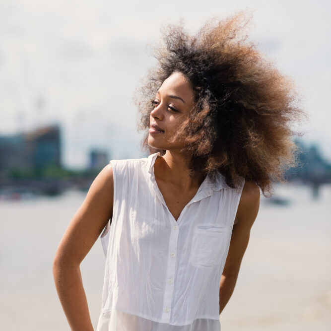 Young black girl wearing a curly afro colored with henna hair dye.