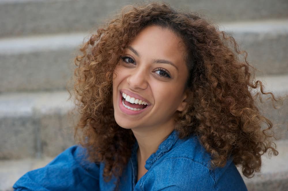 Light skinned African American female with curly hair styled with the shadow root hair technique.