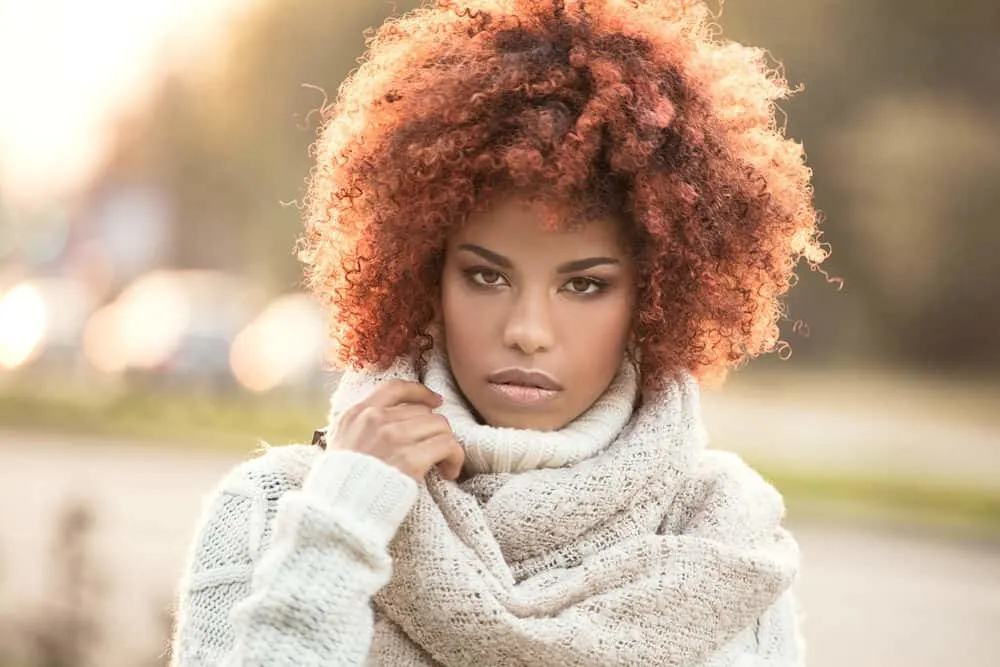 Cute black girl in casual winter attire with chemically lightened hair colored with red for brown hair and pastel purple.