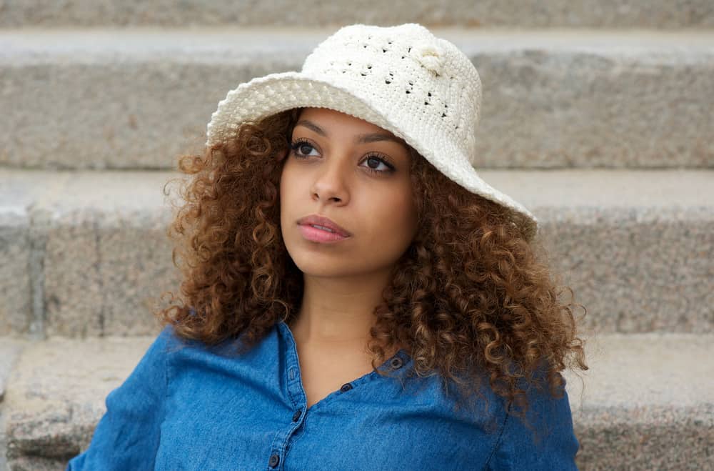 Beautiful young woman with brown curls styled with the shadow root technique.