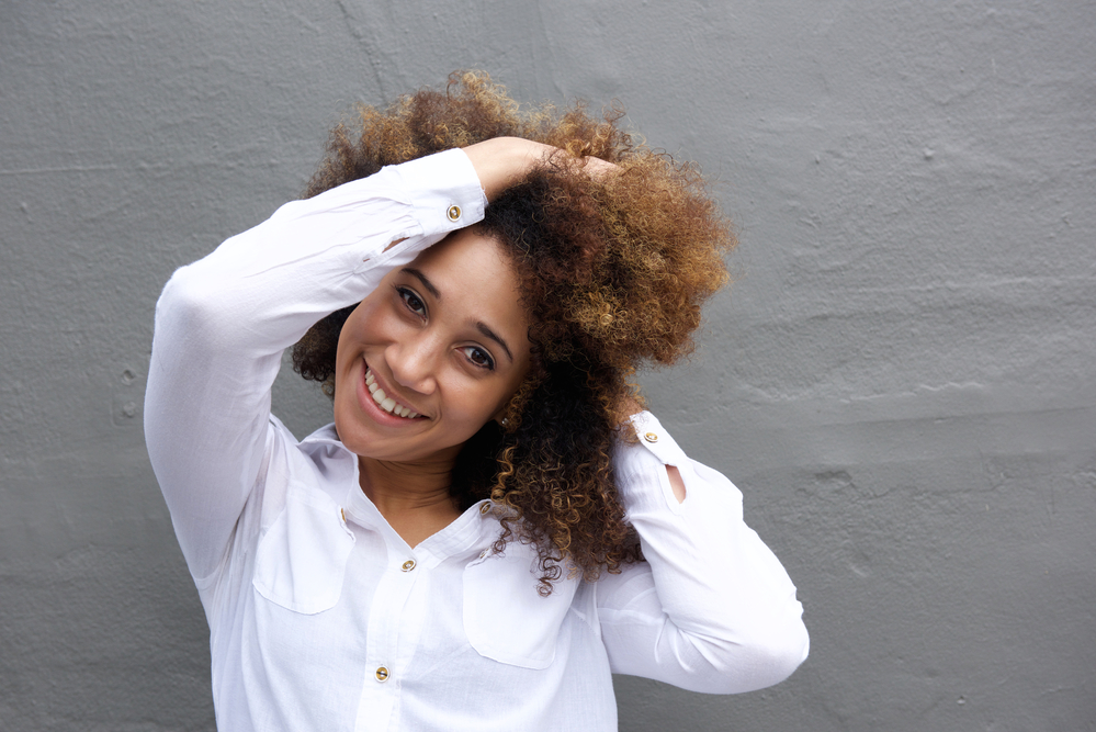 Black woman with light and dark brown colored hair wearing a white dress shirt.