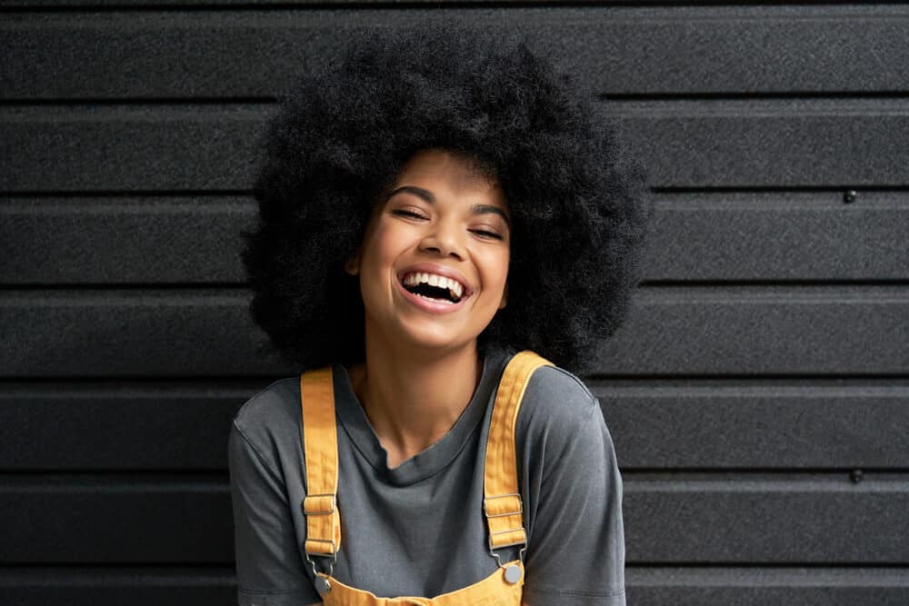 Black girl with a big curly afro hairdo styled with low porosity hair products