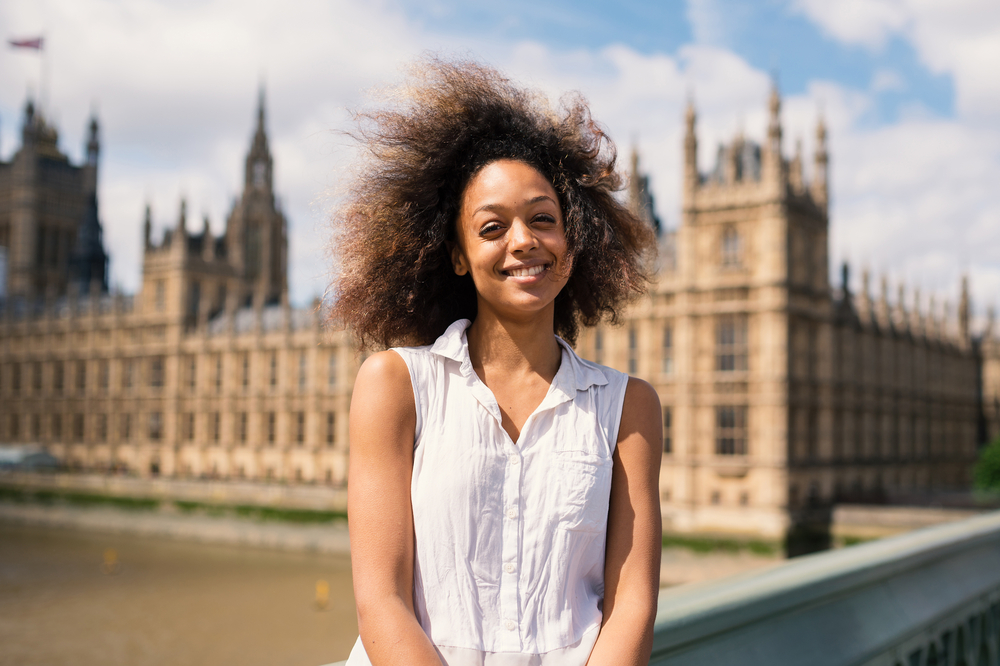 Adult woman wearing a white casual shirt with a curly wash n go style dyed with henna hair dye.