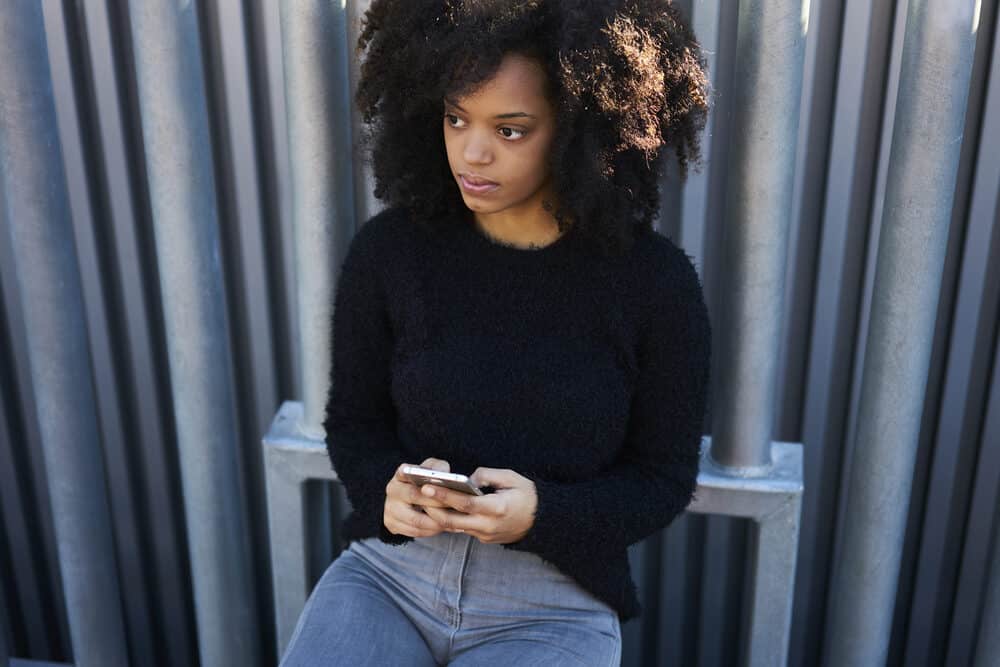 Cute ethnic woman with a curly hair type wearing a twist-out style created with a gentle shampoo and natural oils.