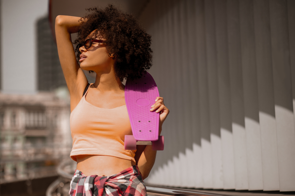 A young female that keeps her naturally curly hair healthier after hair coloring session with color protective shampoo.