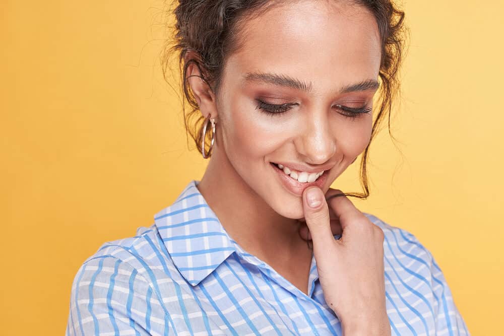 Female with an amazing smile wearing a plaid dress shirt and gold earrings