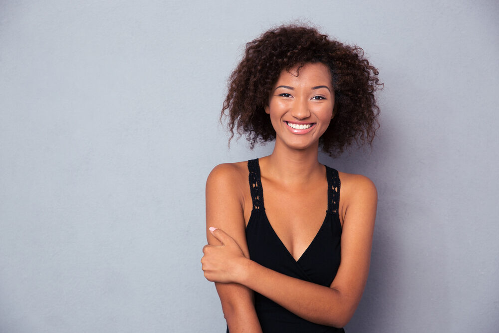 Black lady with a big smile wearing organic makeup since it doesn't clog pores.