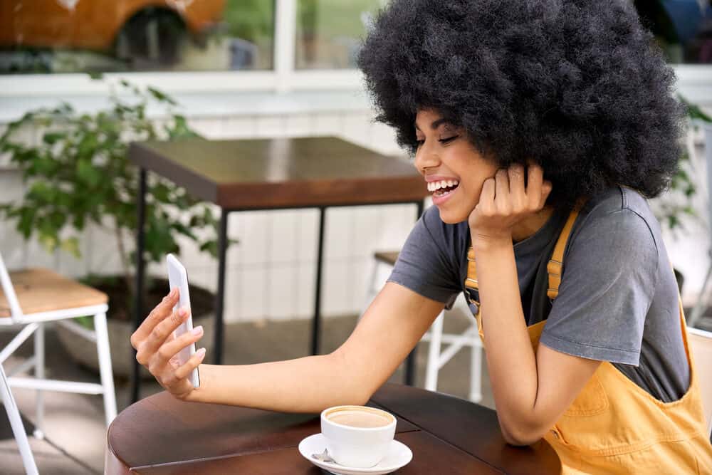 Beautiful mixed race lady sitting outside at a diner with a 4C afro styled with argan oil