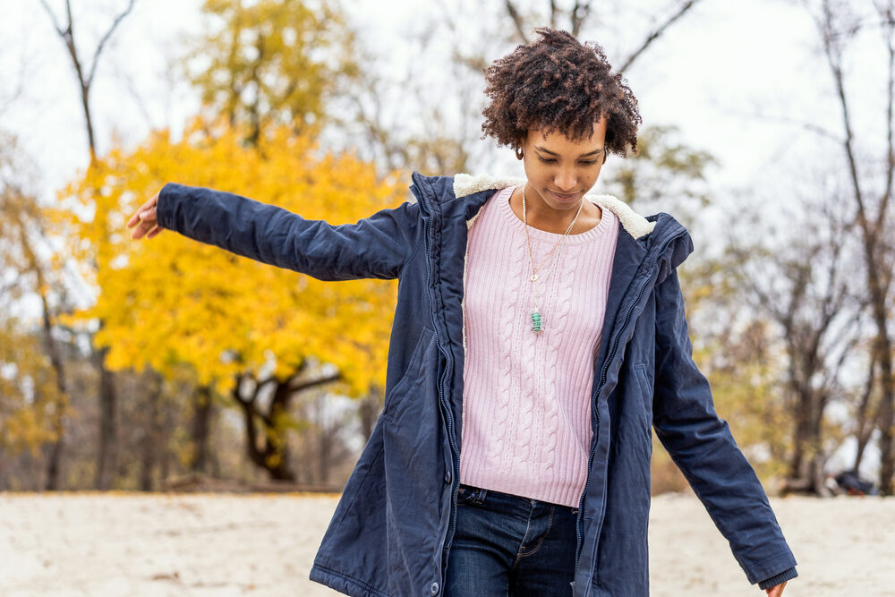 Black girl posing outdoors with curly fine hair in an ombre style from balayage hair dye treatment.