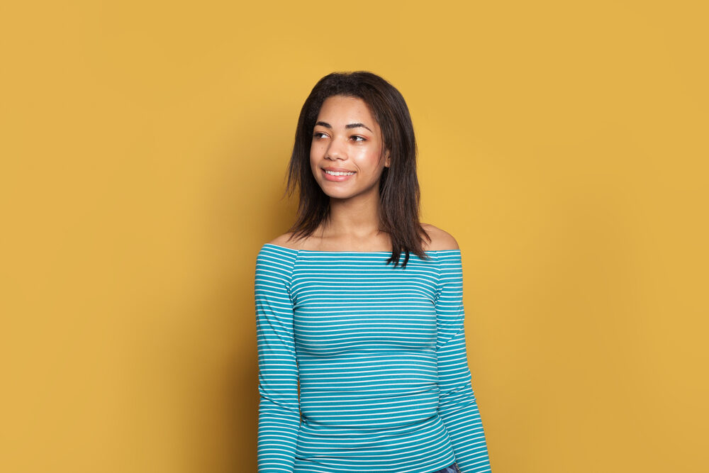 Black woman smiling with straighter strands on top of defined curls underneath.