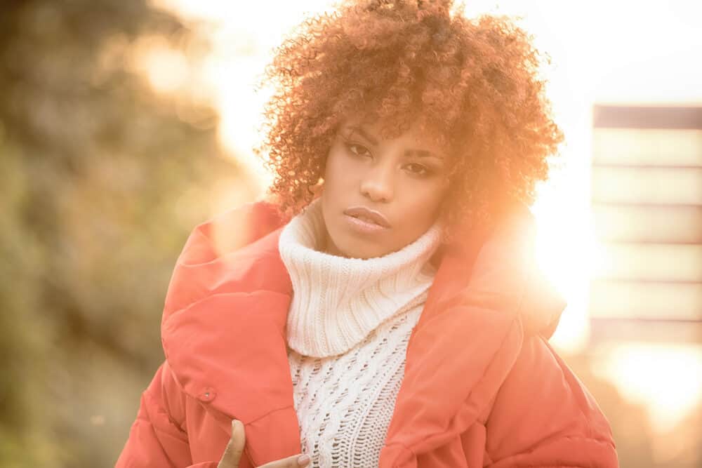 Beautiful black lady with curls styled with Overtone coloring conditioner wearing winter clothes with vibrant colors.