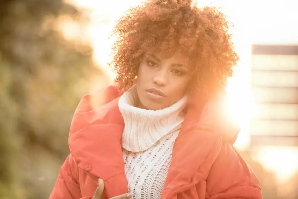 How Long Does Overtone Last on Dark, Light, Bleach Hair and More? 8 Beautiful black lady with curls styled with Overtone coloring conditioner wearing winter clothes with vibrant colors.