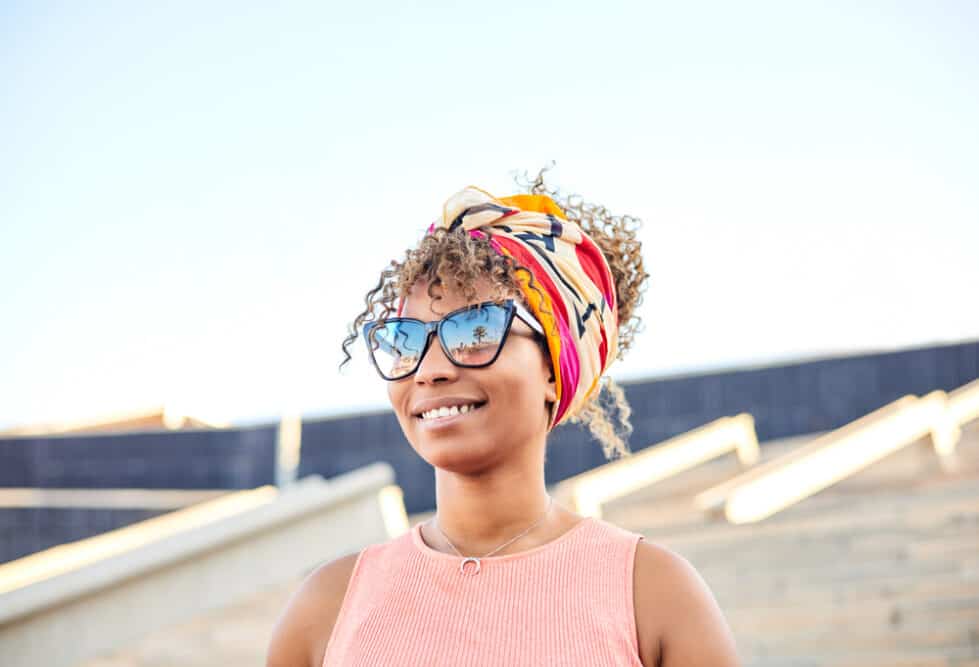 Attractive black woman with sunglasses wearing ombre brown and blond hair styled with African head wrap.