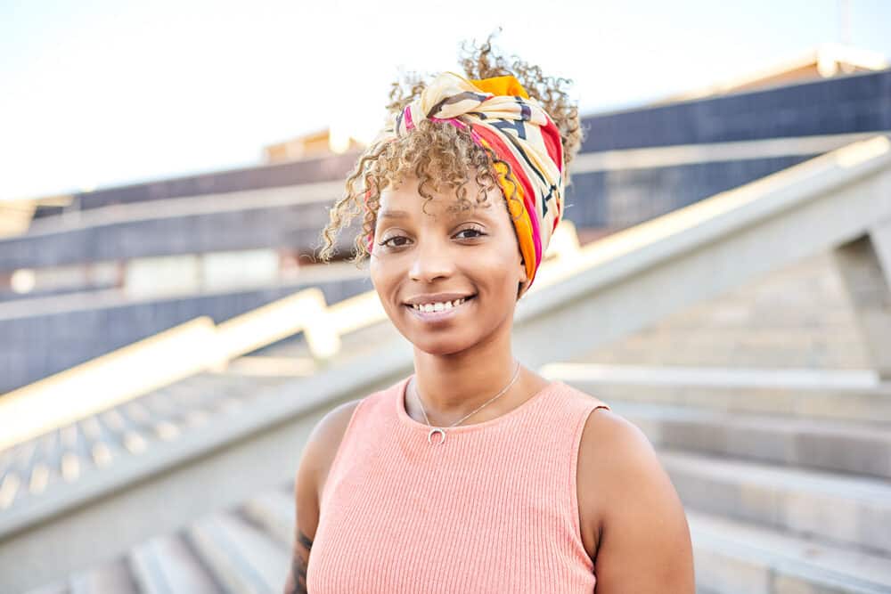 African American lady with a "too" blonde hair color and smooth, cool skin tone wearing a colorful head scarf.