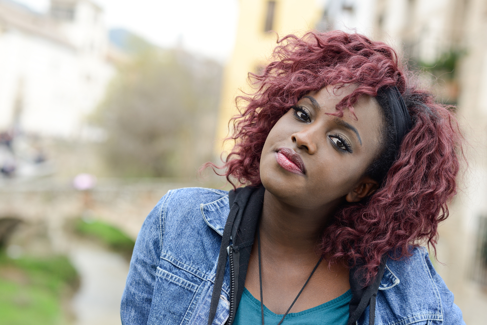 Black lady with darker red curls after dying natural black hair using hair chalk.