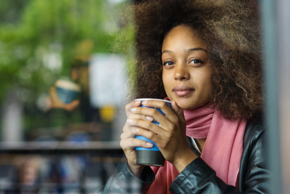 Cute black girl with dark brown hair dyed with black henna drinking coffee.