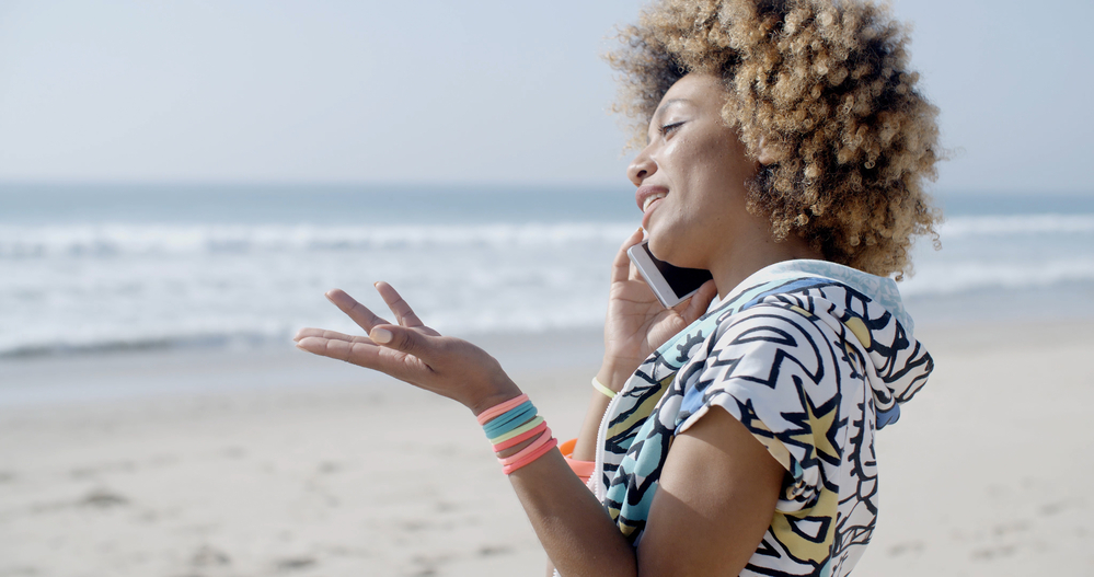 Young woman talking on the phone near the cold water of a beach on the East Coast.