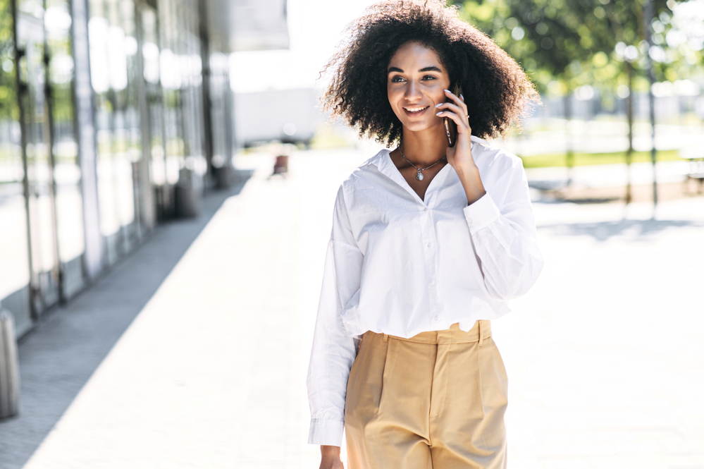 A light-skinned mixed-race woman talking on the phone to a friend about excessive hair loss.