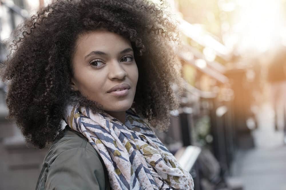 Black girl wearing a silk scarf and green jacket with beautiful type 4 curly hair