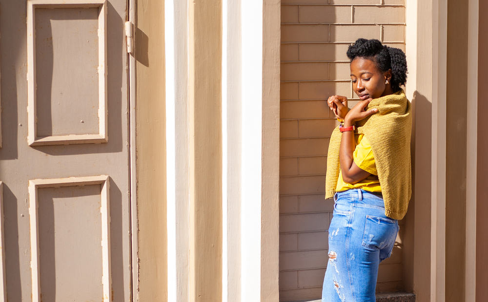 Lady with very thick hair wearing blue jeans with a yellow t-shirt and red Apple watch.