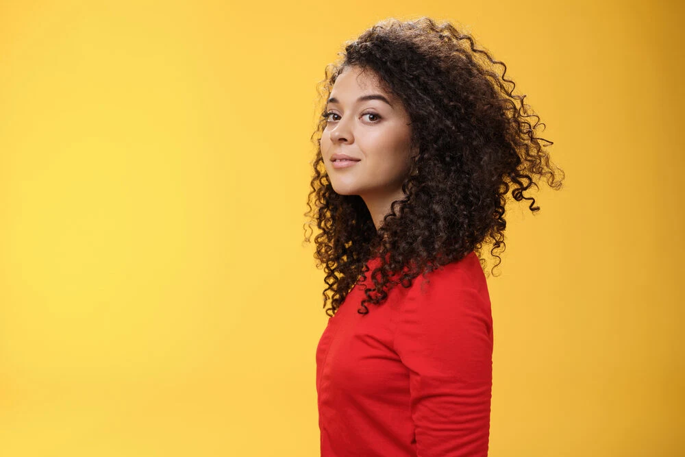 Caucasian female with a wavy hair type wearing a red dress a subtle smile on her face.