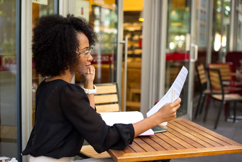 Cute black girl with frizzy hair styled with natural oils working in business attire at a local coffee shop.