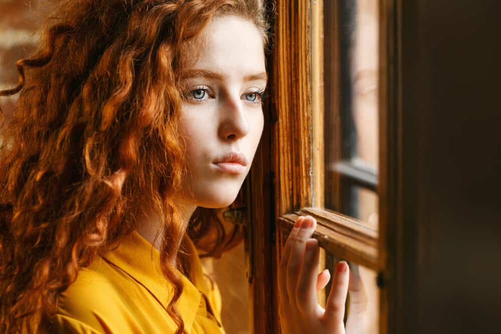 Adult female with blue eyes and a wavy hair type styled with a permanent wave dyed red.