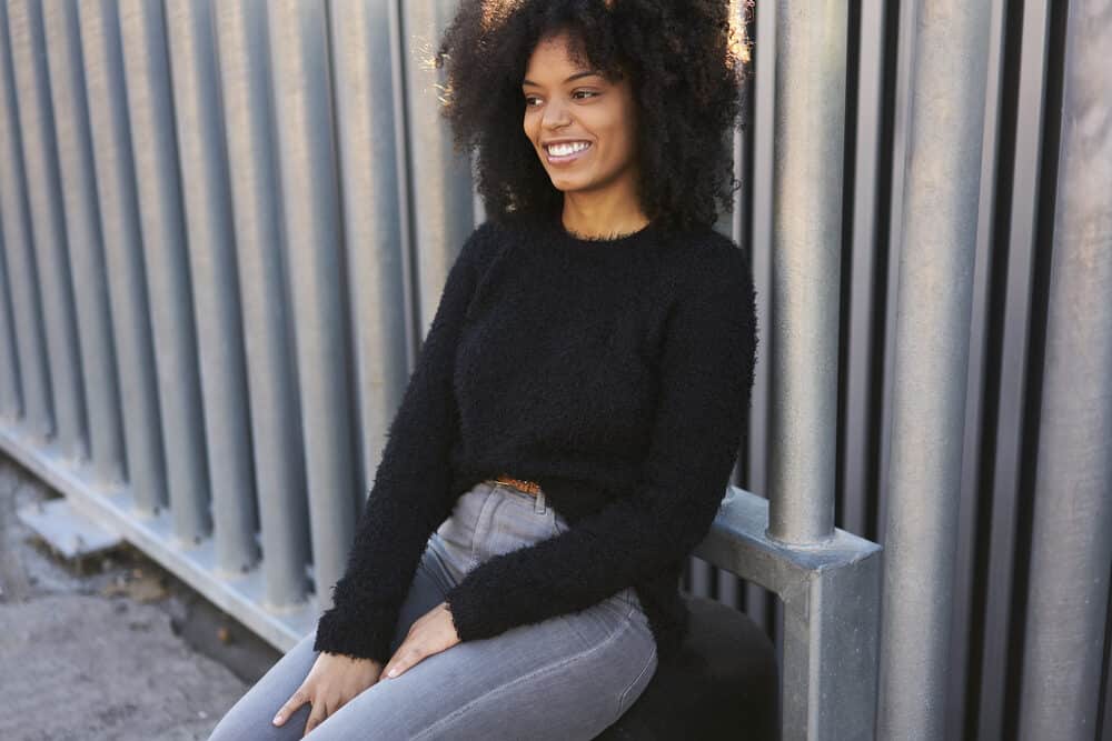 Cheerful young woman with natural hair wearing a curly afro after using a clarifying shampoo to avoid greasy hair.