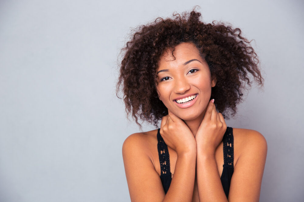 Cheerful young black wearing a kinky twist-out hairdo on 4A curls and natural-looking make-up.