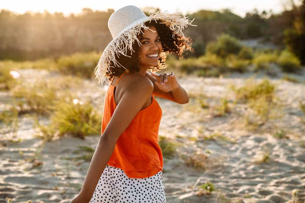 Happy black girl with Cantu shea butter in well-defined curls making her hair smooth with amazing volume.