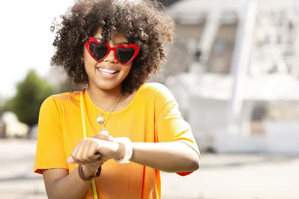 Cute black lady in sunglasses wearing a wash and go hairdo after using salon products.