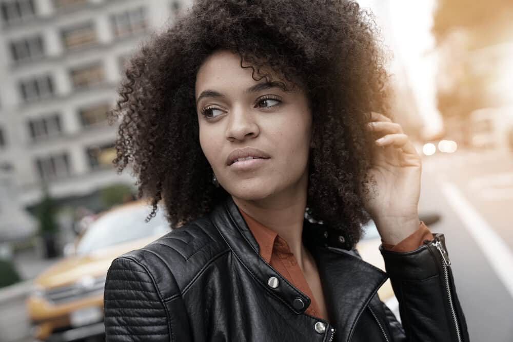 Ethnic girl outside in the sun wearing an orange casual shirt and black jacket