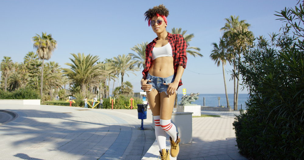 Adorable African American lady with naturally low porosity hair that doesn't absorb moisture walking at the beach.