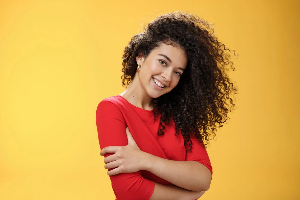 A woman with freshly permed hair gently curled with perm rods and dried with a hair dryer.